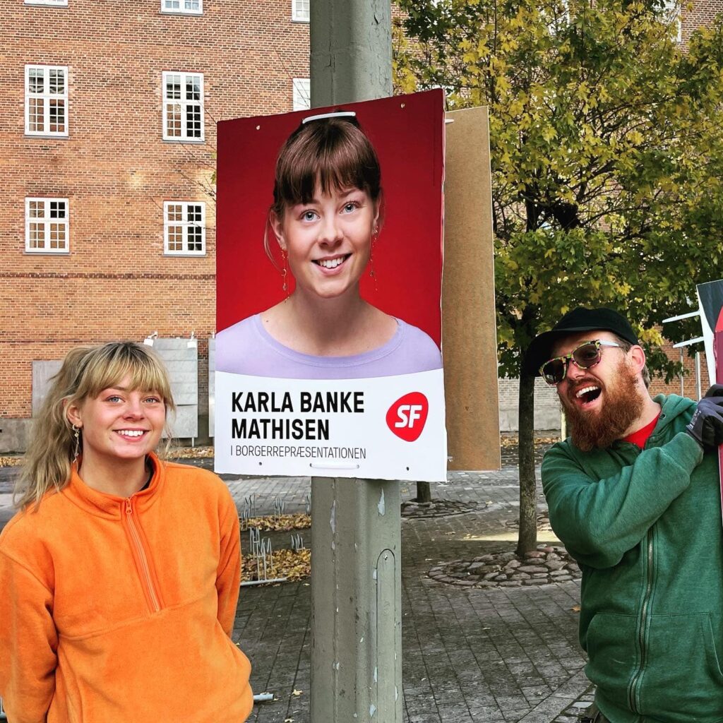 Billede af Benjamin Friis sammen med en valgplakat for Karla Banke Mathisen (SF)