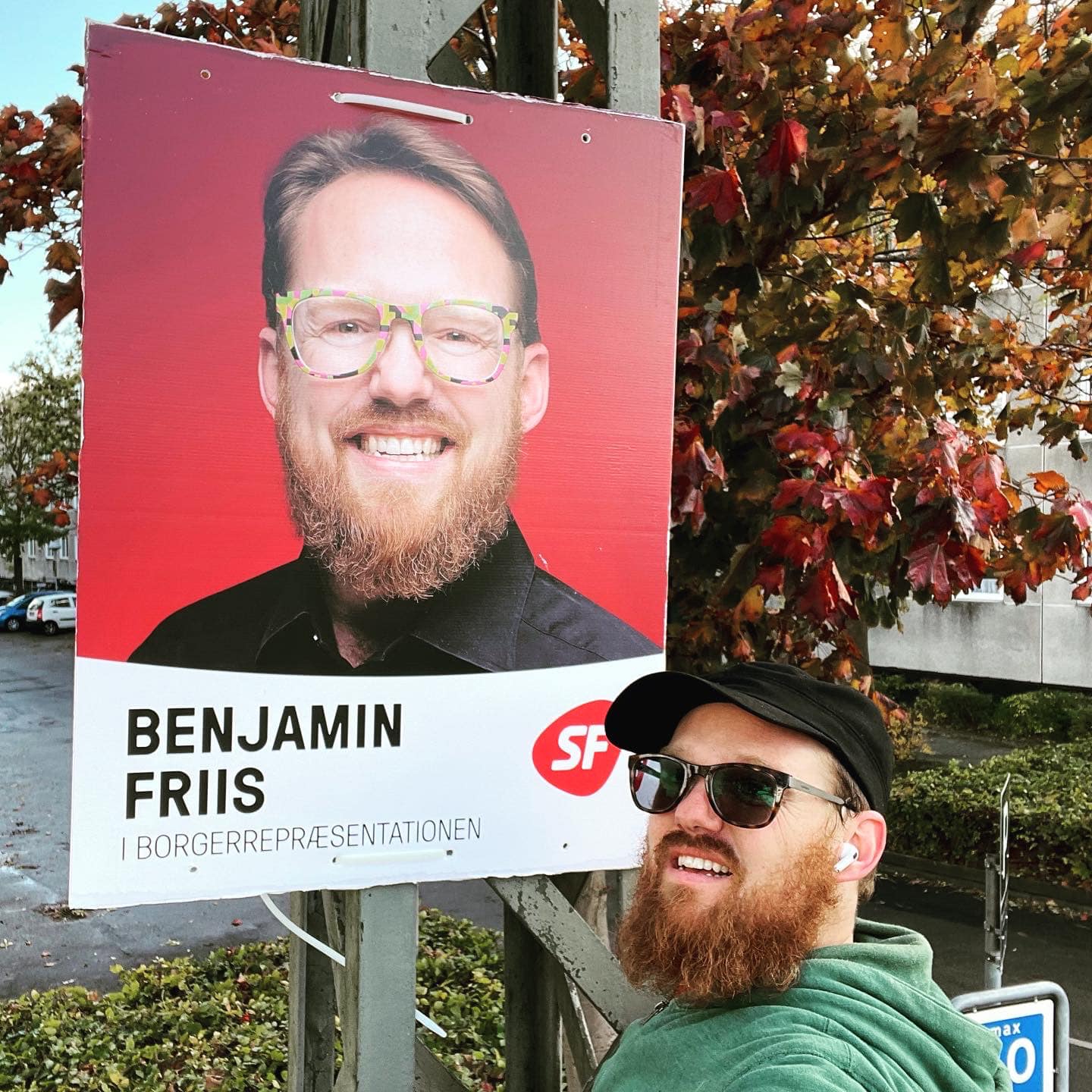 Billede af Benjamin Friis foran en af hans valgplakater